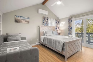A bedroom with a bed, a sofa, a ceiling fan, an air conditioning unit, and a window with curtains. - Incredible Family Escape, Game Room, Waterfront! (Barnstable)