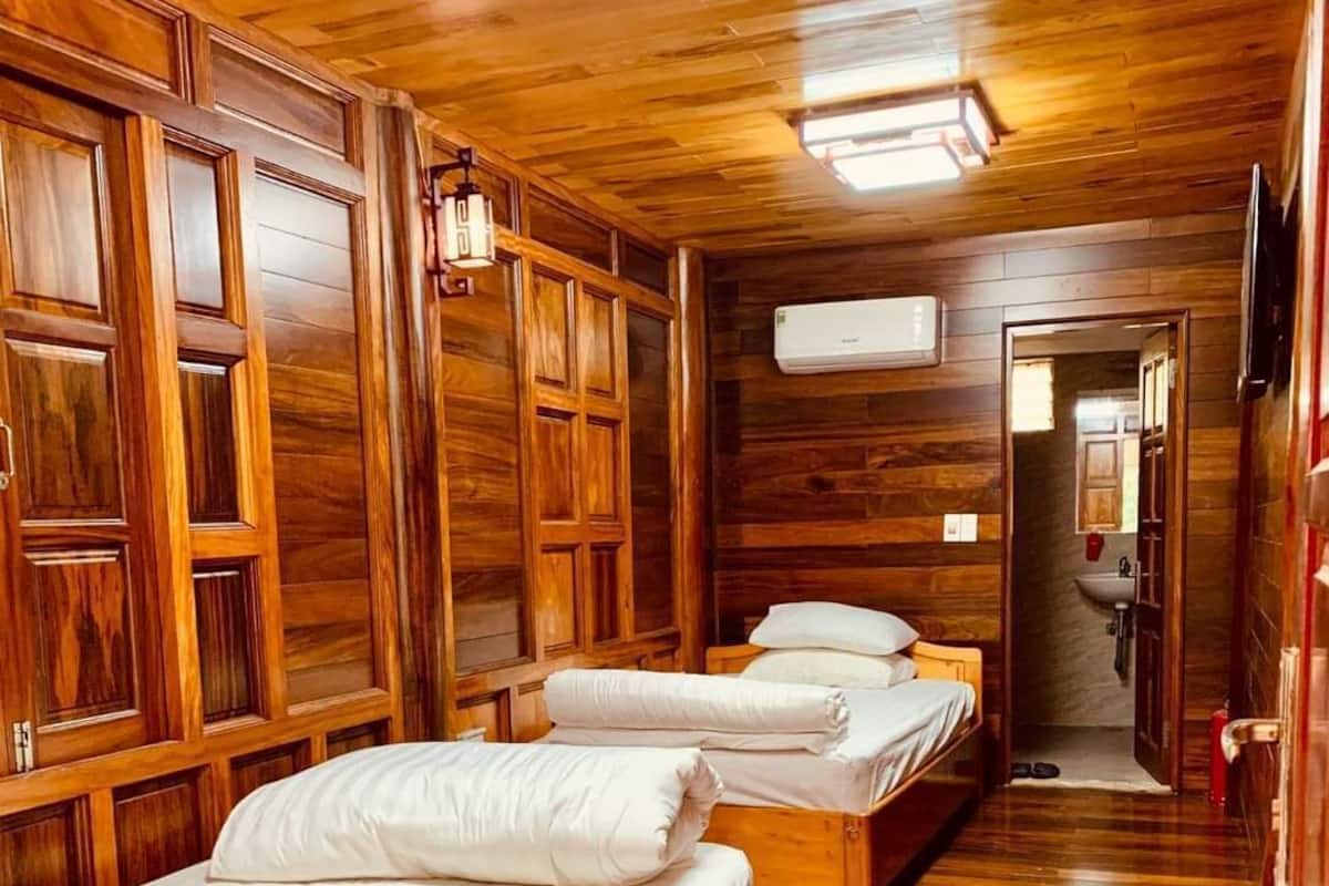 Una habitación tipo cabaña con paredes y suelos de madera, que incluye tres camas de madera con ropa blanca.