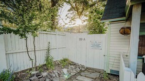 Un giardino recintato da una staccionata bianca, con un muro in pietra e un cartello che indica un viaggio organizzato e alloggio serale.