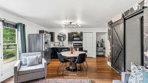A modern kitchen with a dining area, a large window, and a sliding barn-style door.