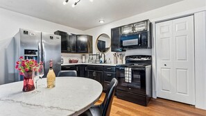 A modern kitchen with a marble countertop, stainless steel appliances, and black cabinetry. - Traveling together but want space and privacy? (Eureka Springs)