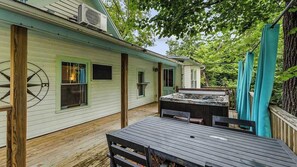 A wooden deck with a table and chairs, a covered grill, and a house with a wheel in the window. - Traveling together but want space and privacy? (Eureka Springs)