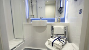 Un bagno moderno con cabina doccia in vetro, lavandino bianco e water con un asciugamano sopra.