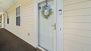 A house with a white door, a wreath, and a porch with a carpeted floor. - Sunny Riverwalk Escape | 1BR Condo on the Waterway & Golf Course (Myrtle Beach)