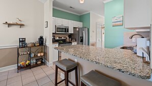 A modern kitchen with granite countertops, stainless steel appliances, and a teal accent wall. - Sunny Riverwalk Escape | 1BR Condo on the Waterway & Golf Course (Myrtle Beach)