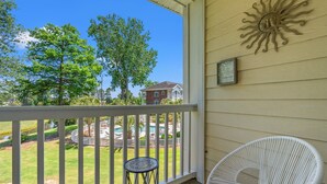 A balcony with a white railing, a white wicker chair, and a small round table. - Sunny Riverwalk Escape | 1BR Condo on the Waterway & Golf Course (Myrtle Beach)