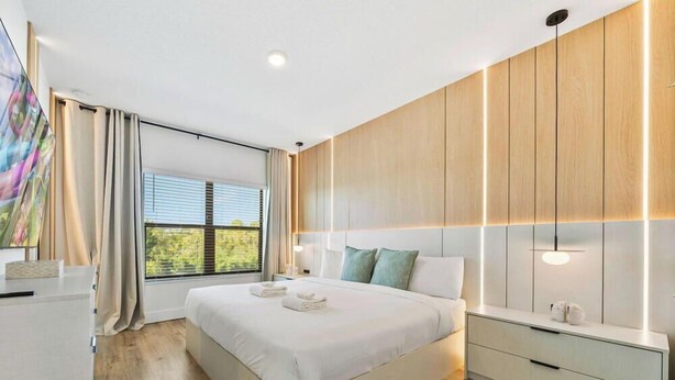 Een moderne hotelkamer met een groot bed, een televisie en een wand van hout.