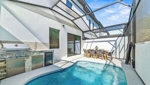 Une piscine avec un barbecue et du mobilier d’extérieur.