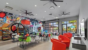 Un espace intérieur accueillant, doté de ventilateurs de plafond, d’une fresque murale et de différents types de sièges.
