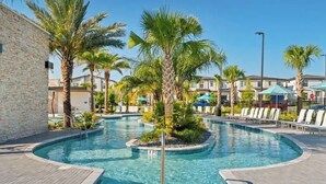 Une piscine avec un palmier et des chaises longues.