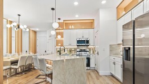 Una cocina moderna con armarios blancos, electrodomésticos de acero inoxidable e isla de mármol.