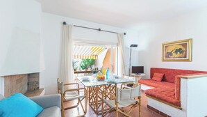 A cozy living room with a sofa, a dining table with chairs, and a TV on a stand. - Casa Corsara (Santa Teresa di Gallura)