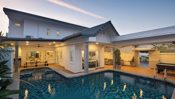 A modern house with a swimming pool, a dining area, and a covered outdoor space.