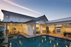 A modern house with a swimming pool, a dining area, and a covered outdoor space.