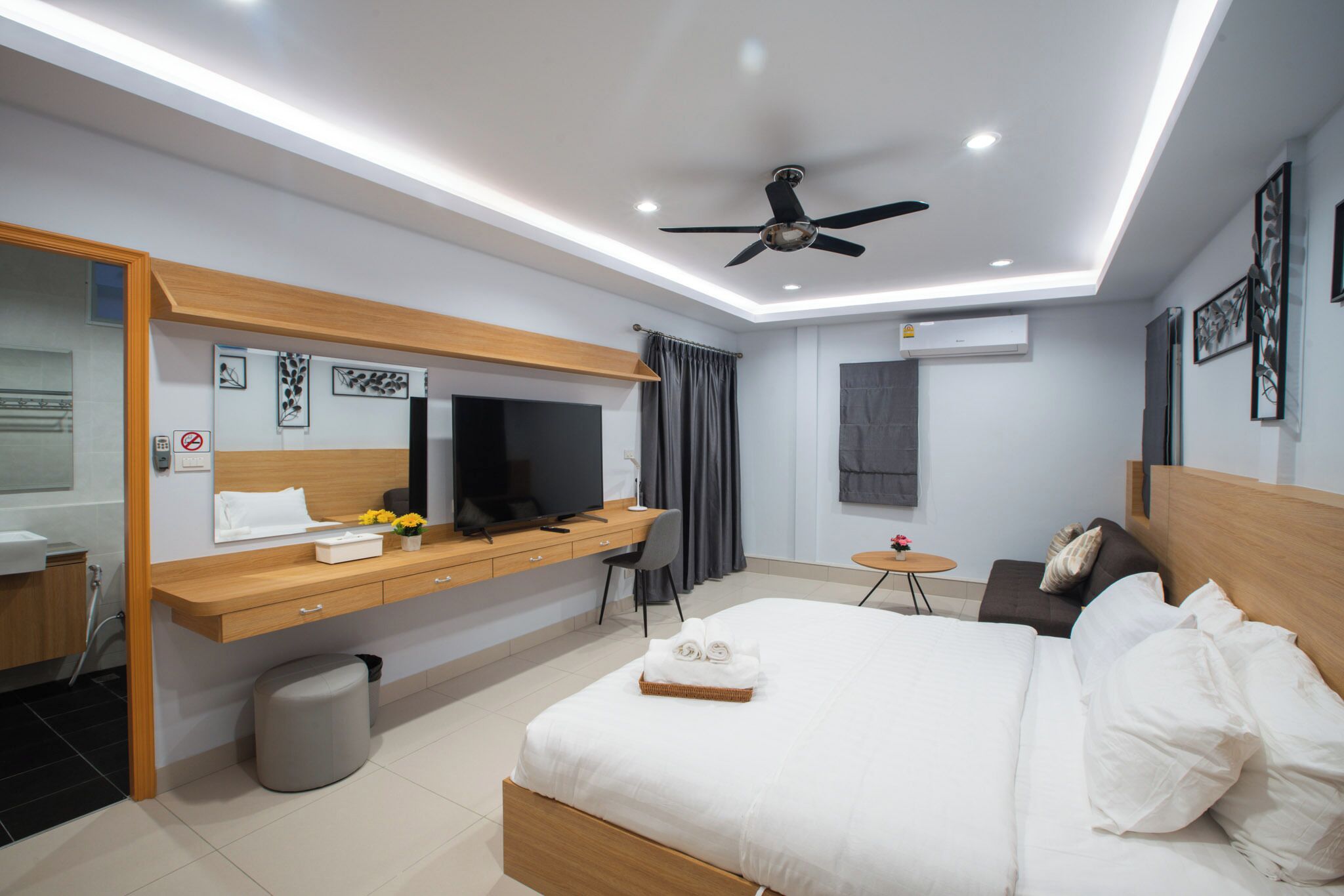 Een moderne hotelkamer met een bed, een bureau, een televisie en een plafondventilator.