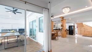 A spacious living area with a dining table, a kitchen, and a staircase leading to an upper floor.