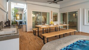 A modern kitchen with a sink, wooden flooring, and a dining area with a table and benches.