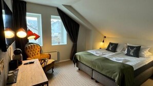 Habitación de hotel con cama, escritorio, silla y ventana.