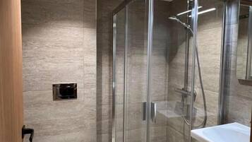 Un baño moderno con ducha de vidrio, inodoro blanco y lavamanos.