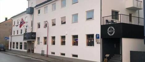 Un edificio de varios pisos con fachada plana, varias ventanas y un pequeño balcón en el nivel superior.