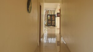 Un pasillo con suelo pulido que conduce a una habitación con puerta de madera y puerta de cristal.