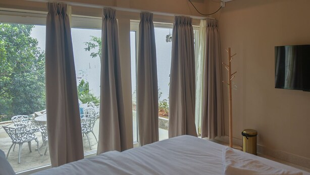 Una habitación de hotel con cama, televisión y ventana con cortinas.