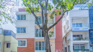 Un edificio de varios pisos con un árbol en la parte delantera, un cartel con el letrero 'INTEGROM' y coches aparcados.