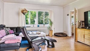 Ein modernes Wohnzimmer mit einem schwarzen Ledersofa, einem Couchtisch und einem Fernseher auf einer Holzkommode.
