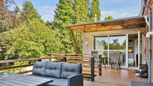 Eine Terrasse im Freien mit einer Couch, einem Tisch und einem Stuhl.
