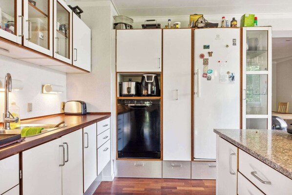 A modern kitchen with white cabinets, a built-in oven, and a refrigerator with magnets. - Charming Town Apartment in Gram (Gram)