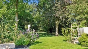 Ein gepflegter Garten mit vielfältigen Pflanzen und einer hölzernen Struktur.