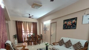A spacious living room with a sofa, chairs, a coffee table, and a dining area with a table and chairs. - Staeg 2bhk Heart of the city (Bhopal)