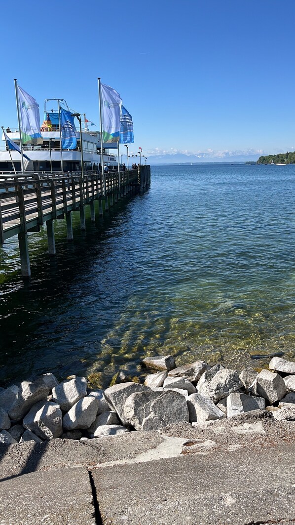 A pier extending into a calm lake with clear water, surrounded by rocks and a clear sky.