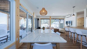 Une cuisine moderne dotée d’un grand îlot en marbre, de touches de bois et de grandes fenêtres offrant une vue sur l’extérieur.