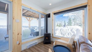 Une pièce chaleureuse avec une grande fenêtre, une cheminée et une vue sur un paysage enneigé.