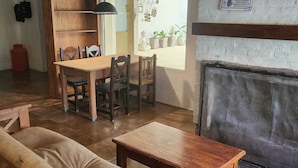 A cozy living room with a wooden dining table and chairs, a fireplace, and a sofa. - Hosteria Santa Maria (Mercedes)