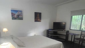 A hotel room with a bed, a TV, a desk, and a chair. There are two paintings on the wall. - Hosteria Santa Maria (Mercedes)