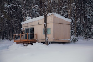 A wooden cabin with a balcony, surrounded by snow-covered trees.