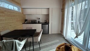 A compact kitchen with a dining area, wooden walls, and a large window.