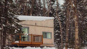 A wooden cabin with a balcony, surrounded by snow-covered trees.
