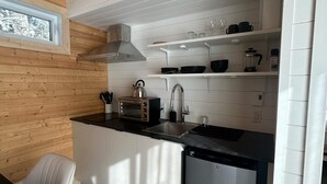 A compact kitchen with white cabinetry, a built-in oven, a coffee maker, and a dishwasher.