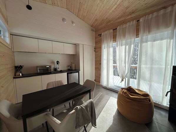 A modern kitchen with white cabinets, a black countertop, and a dining area with a table and chairs.