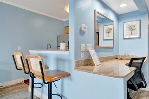 Un baño moderno con pared azul, un lavamanos, un espejo y dos sillas.