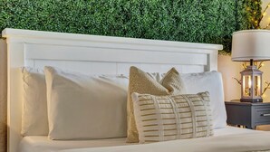 A neatly made bed with white linens and decorative pillows, a white headboard, and a nightstand with a lamp. - LA Kids Suite | Waterfront w/ Heated Pool Access (Tampa)