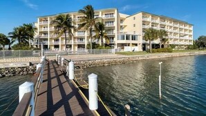 A waterfront hotel with multiple balconies, a boardwalk, and palm trees. - Waterfront Condo w/ Private Balcony & Heated Pool (St. Petersburg)