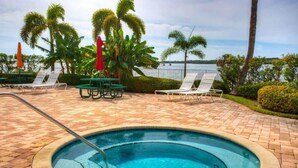 A pool area with lounge chairs, a hot tub, and a view of the water. - Waterfront Condo w/ Private Balcony & Heated Pool (St. Petersburg)