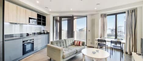 Relax in a stylish living area with a sofa, coffee table, and dining table, offering a view of the city.