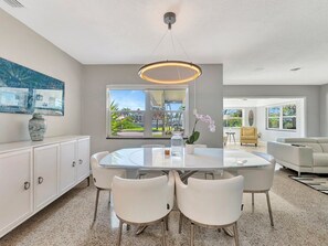 Gather around this elegant dining area where your group can share meals under a modern chandelier. Fresh orchids set a welcoming tone, and the open layout flows seamlessly into your comfortable living space. - Waterfront heated pool, dock, kayaks and bikes (St. Pete Beach)