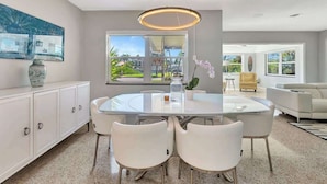 A modern kitchen with a round dining table, white chairs, and a pendant light.