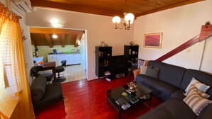 Una sala de estar con un sofá, una mesa de centro y una estantería. Se ve una cocina al fondo.